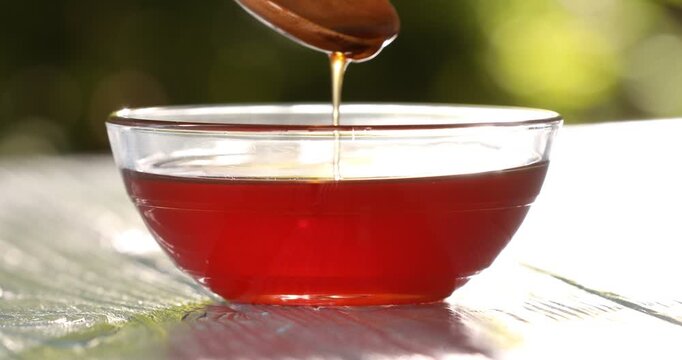 Taking maple syrup with spoon at wooden table outdoors, closeup