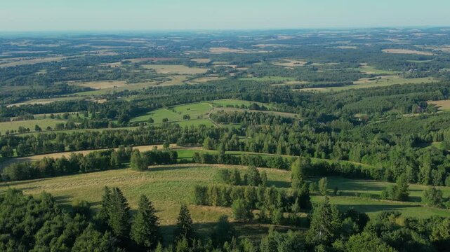 Aerial panorama of rolling farmland and forested hills under clear skies