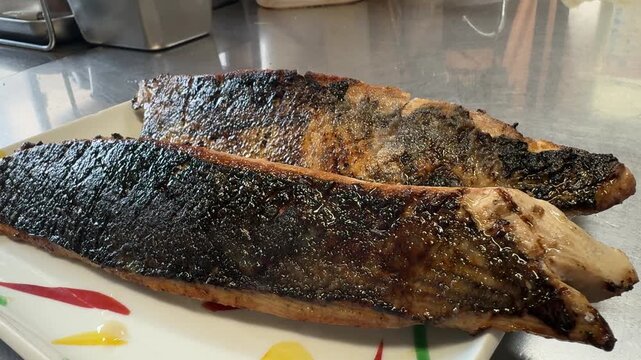 Freshly seared katsuo no tataki bonito fillets served on a white plate at an izakaya kitchen in Japan