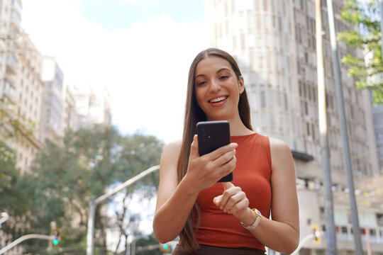 Portrait of Brazilian business woman using mobile phone on sunny day in Republica Square, Sao Paulo, Brazil