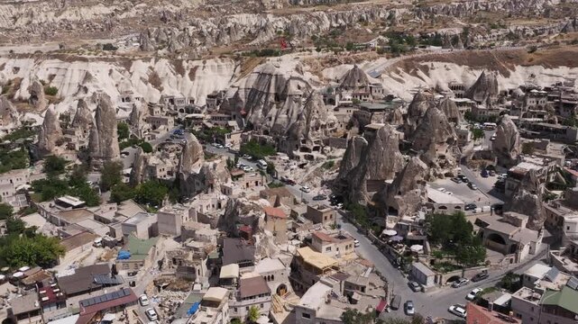 Aerial drone cinematic shot moving over unique stone fairy chimneys and historic dwellings in goreme cappadocia turkey.