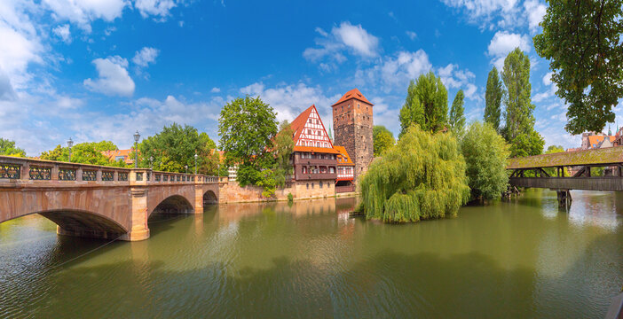 Panoramic view of the Pegnitz River with stone and covered bridges, traditional buildings and historic towers in Nuremberg, Germany.