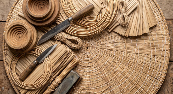 Cinematic overhead lay of Vietnamese Non La hat crafting tools on palm mat