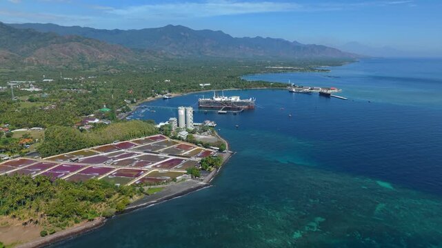 Aerial view of the Cinta Natomas Floating Storage and Offloading ship moored in the coastal waters near industrial facilities and lush greenery in Buleleng Regency, Bali, Indonesia.