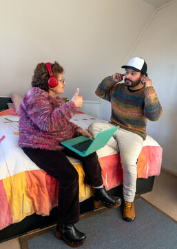 An elderly woman listens to music with red headphones