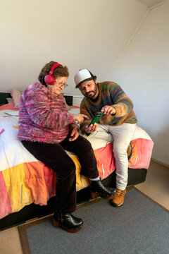 An elderly woman learns to listen to music with headphones with her son's help