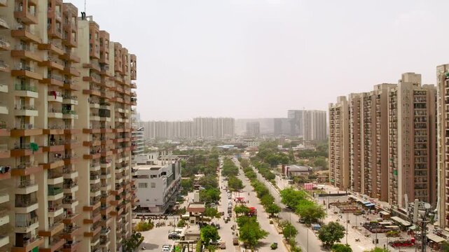 Aerial view of modern residential apartment buildings lining a central road with lush trees and urban infrastructure in New Delhi, Delhi, India.