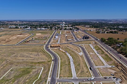 Aerial view of a suburban residential development site with newly paved roads, construction progress, and open land under a clear blue sky in Westminster, Colorado, United States.