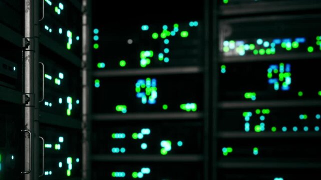 Rows of server racks are shown with green and blue lights blinking in a dark tech facility at night. The setting highlights technology and digital infrastructure.