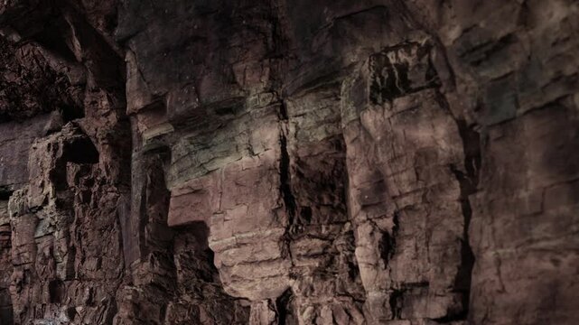 The scene shows rock formations inside a cave. The cave walls display different textures and colors. Natural light creates shadows, highlighting the details on the surface.