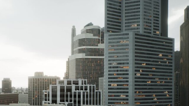 Tall buildings stand close together in a downtown area. The sky is cloudy with some light visible in the evening. The structures showcase a mix of designs and materials.