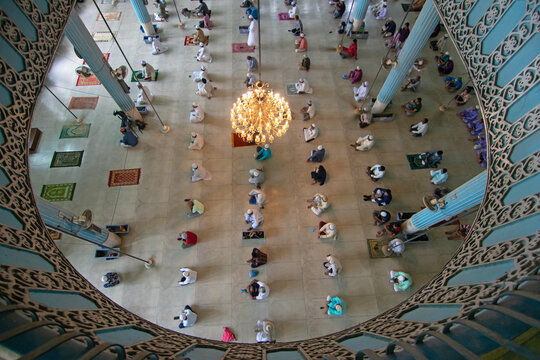 Dhaka, Bangladesh - 21 August 2020: Aerial view of Baitul Mukarram National Mosque with worshippers praying on mats beneath a large chandelier in the prayer hall.