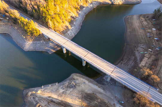 Aerial view of a bridge spanning a calm reservoir surrounded by trees and natural landscape in Czech Republic.