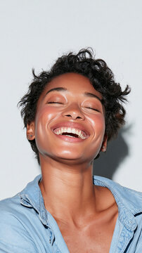 Joyful Radiance: A young woman beams with uninhibited laughter, her eyes closed in pure bliss and her face illuminated with a warm, healthy glow. Her short.