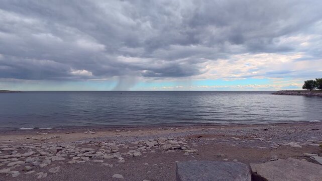 Rain shaft or rain curtain over Lake Ontario, view from a beach in Bluffers Park, Scarborough, Ontario, Canada