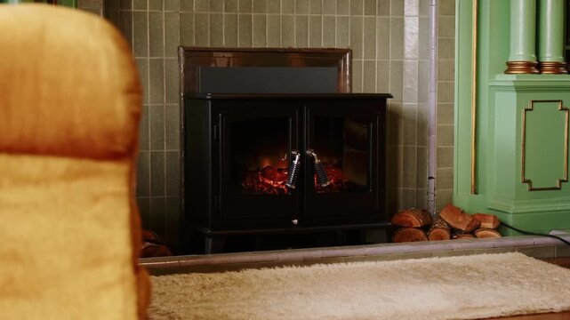 Cozy living room interior featuring warm electric fireplace with burning logs and yellow armchair in front.