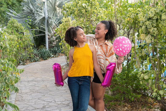Young sisters celebrating birthday with number 11 balloons