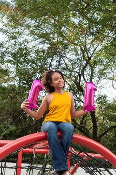 Girl celebrating eleventh birthday holding number 11 balloons