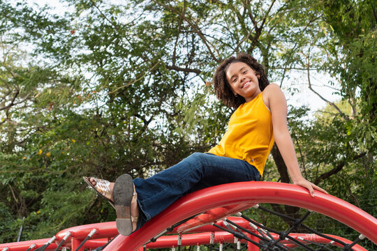 Happy girl playing on a red playground climbing frame