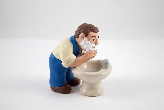 サロペット姿で顔を洗う男性の人形