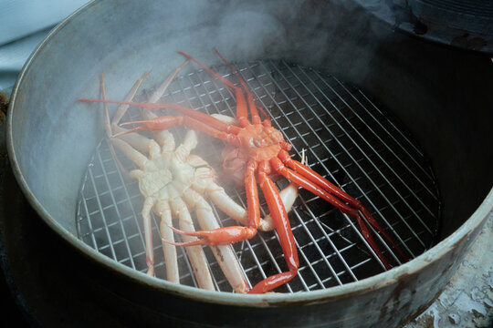 Premium winter crustaceans cooking inside a large traditional metal steamer with rising hot vapor. This authentic culinary preparation scene captures regional coastal gastronomy for food tourism media