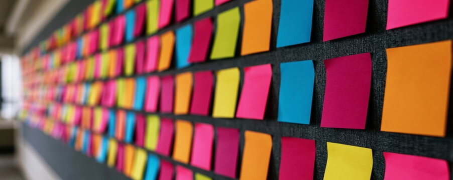 Colorful sticky notes arranged on dark grey office wall representing agile project management and professional task organization for team productivity