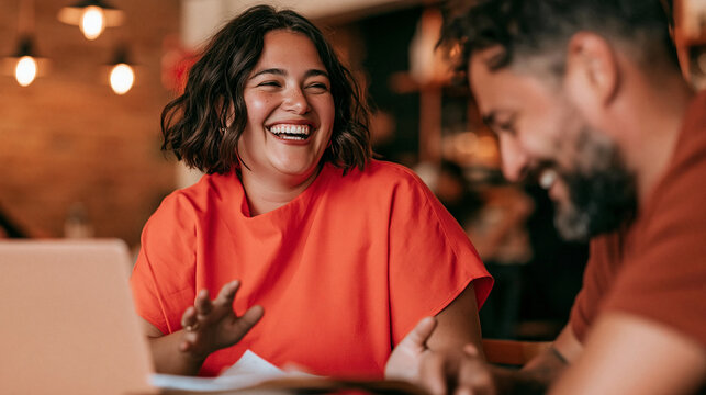 Joyful Conversation at a Cafe: A radiant woman laughs heartily while engaging in a lively conversation with a man at a cozy cafe, their faces illuminated by warm, inviting light.