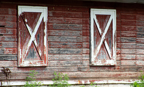 Weathered red barn wall background with white X cross door panels and peeling paint