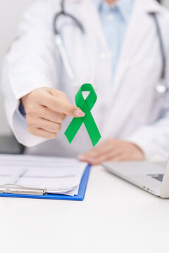 Doctor give green ribbon for concept of July Eye Injury Prevention month, January Glaucoma Awareness month, February Gallbladder and Bile duct and October Liver cancer. Health and world cancer day