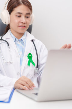 doctor using laptop for telehealth, online consultation and meeting about green ribbon for July Eye Injury Prevention month, February Gallbladder and Bile duct and October Liver cancer Awareness month