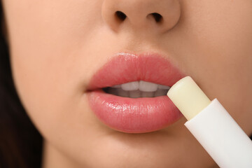 Naklejka premium Young woman applying lip balm, closeup