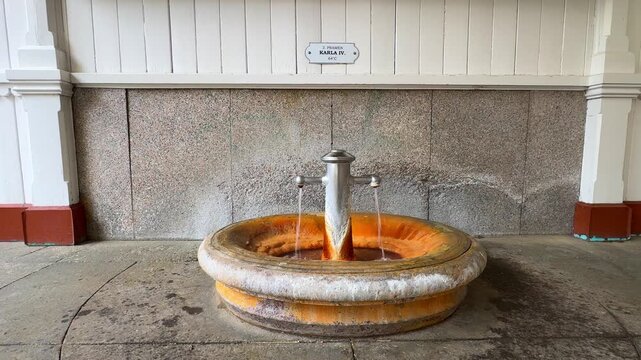 A fountain in Karlovy Vary offers mineral water. The spot shows the various textures and colors of the fountain's surface. Spring 2, Charles IV Spring, Pramen Karla IV in Market Colonnade