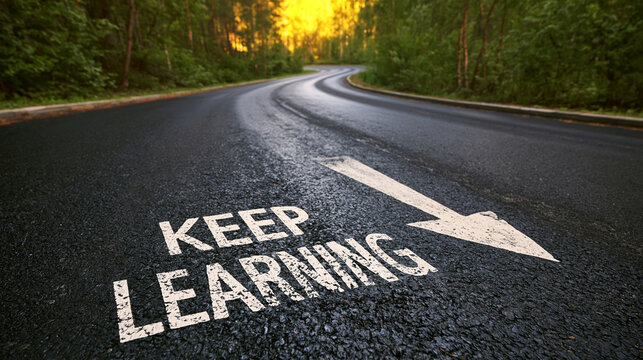 Keep learning written on an asphalt road with an arrow pointing toward a sunrise. This metaphor represents education and continuous personal development for success.