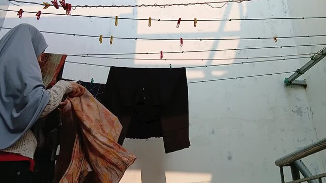 Woman Taking Dry Clothes Off a Clothesline After Air Drying Outdoors