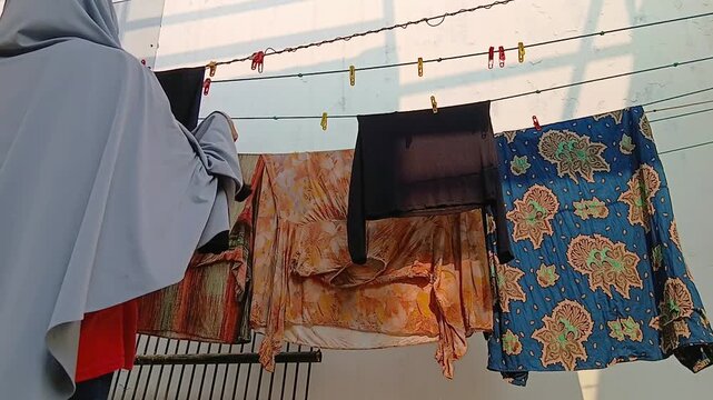 Woman Taking Dry Clothes Off a Clothesline After Air Drying Outdoors