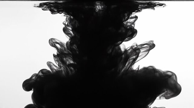Black ink swirling in water creating abstract smoke patterns concept. Black ink swirling in water creating abstract dark smoke patterns on a white background