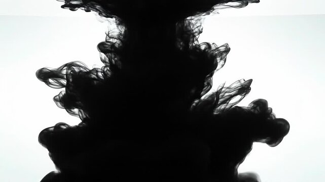 Black ink swirling in water creating abstract dark cloud shapes on white background