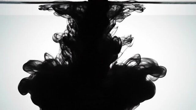 Black ink swirling in water creating abstract smoke effect with white background