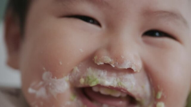 Asian baby boy self feeding sweet corn using baby led weaning method at home.	
