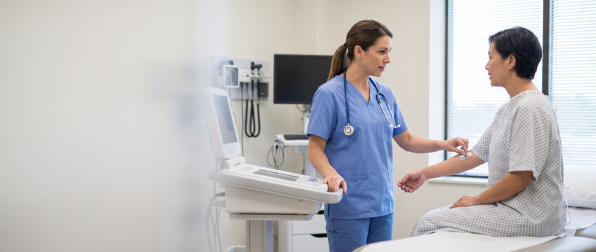 Nurse prepares adult patient for routine diagnostic procedure, positioning medical sensor and checking equipment while providing clinical support, patient care and hospital nursing services.