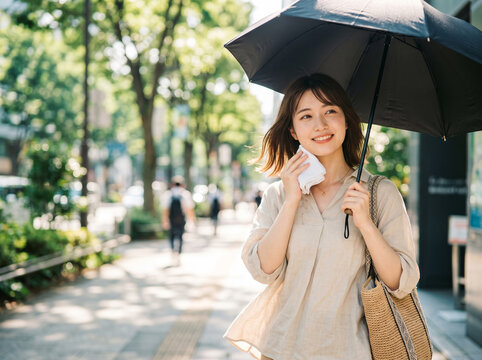 ハンカチで汗を拭いながら日傘を差して歩く微笑む女性