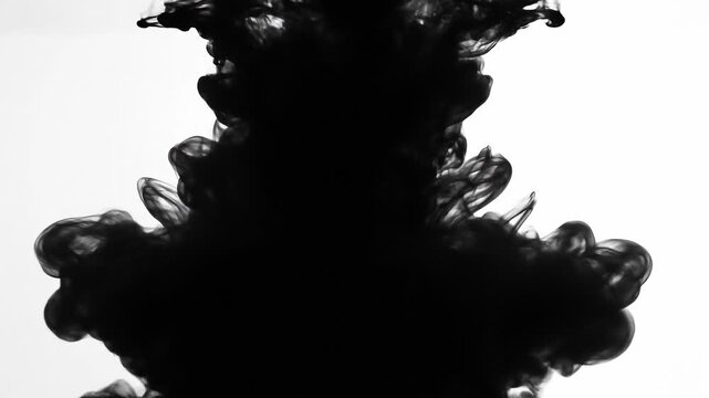 Black ink swirling in water with abstract shapes and fluid motion on white background