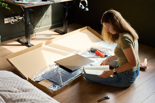 Woman reading instructions before assembling shelving at home
