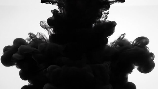 Black ink swirling in water creating abstract dark cloud shapes on white background