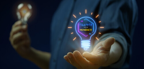 Naklejka premium Businessman hands supporting glowing lightbulb with human head profile gear and quote Change your Mindset. Positive mindset transformation, cognitive shift, and motivational thinking concept.