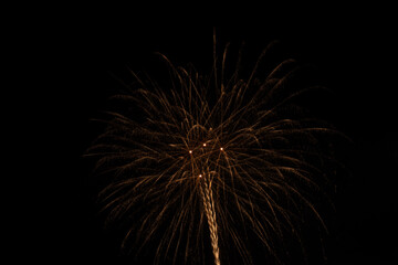 Fototapeta premium Golden fireworks sparkling and exploding brilliantly in the dark night sky during a summer festival celebration