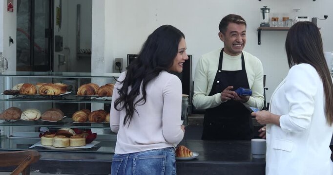 young latin man barista preparing and selling coffee and customer paying with credit card in a coffeeshop in Mexico Latin America