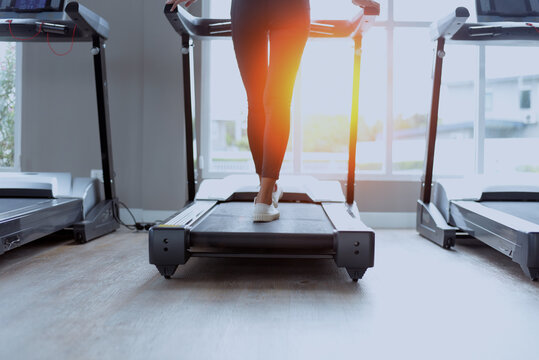Woman legs walking on treadmill in gym with sunlight. Real photo created by human, not AI.