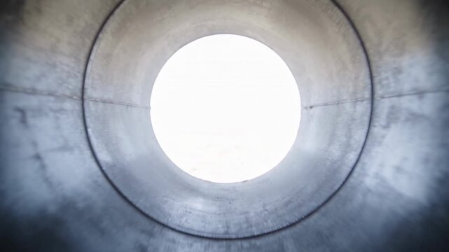 Camera flying down the inside of a steel pipe toward the opening