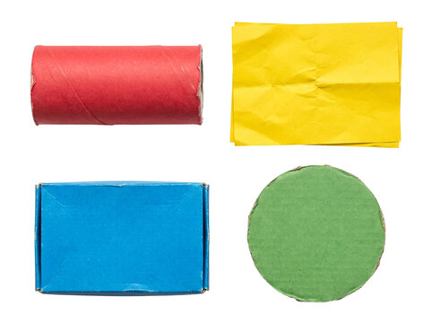 Colorful collection of recycled cardboard and paper items: red tube, yellow paper, blue box, green circle.